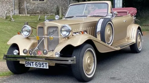 Front view of gold Beauford wedding car with burgundy convertible roof folded down and chrome details.
