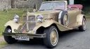 Front view of gold Beauford wedding car with burgundy convertible roof folded down and chrome details.