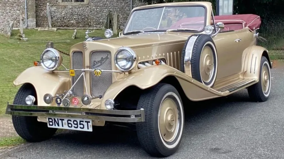 Front view of gold Beauford wedding car with burgundy convertible roof folded down and chrome details.