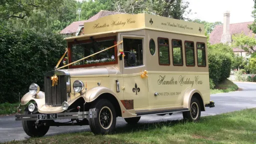 Cream and gold Asquith Mascot 8-seater vintage wedding bus parked in a garden setting