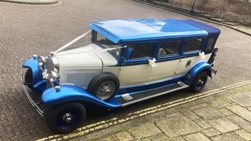 Elevated front view of the blue and white Bramwith Landaulette wedding car with its semi-convertible roof open