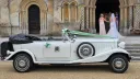 White Beauford Convertible wedding car with dark green interior parked outside a church with the bride in the background entering the Church