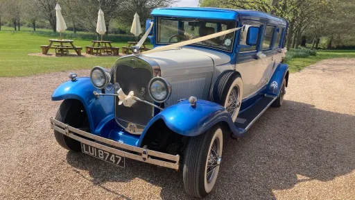 Blue and white Bramwith Landaulette wedding car decorated with white wedding ribbons