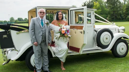 Bride and her father stepping out of a white Imperial Viscount Landaulette wedding car with cream interior