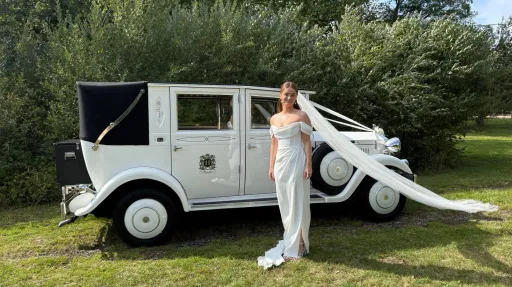 Bride standing beside a white Imperial Viscount Landaulette vintage wedding car with the rear roof lowered