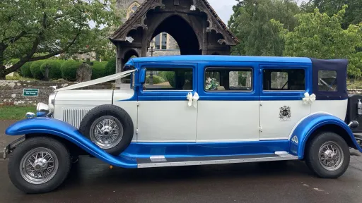 Left side view of the blue and white Bramwith Landaulette decorated with wedding ribbons