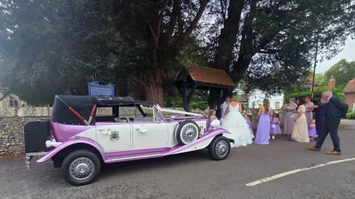 Lilac and white Beauford Convertible wedding car with its roof lowered while on wedding duties