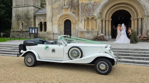 Right side view of a white Beauford Convertible wedding car parked outside a church in Waterlooville
