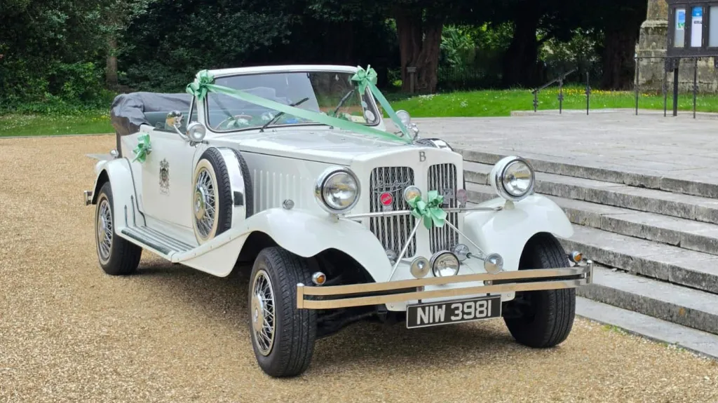 Front three-quarter view of a white vintage Beauford Convertible wedding car with dark green interior in Hampshire