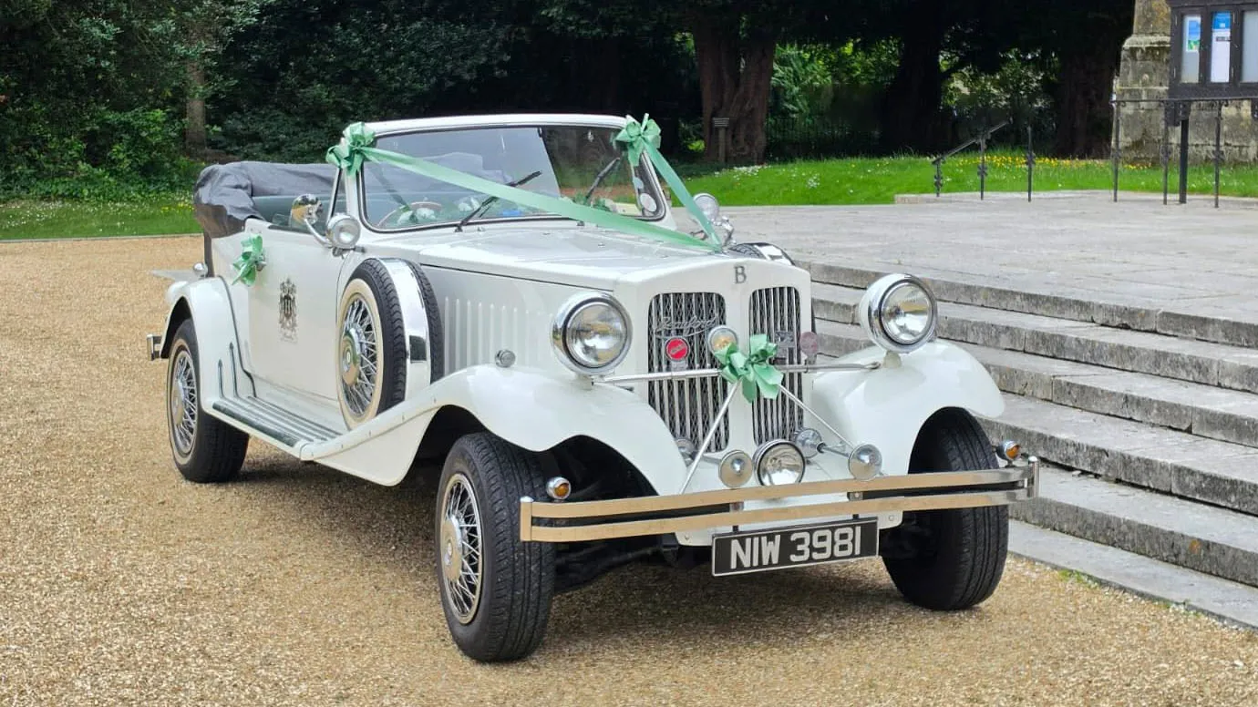 Front three-quarter view of a white vintage Beauford Convertible wedding car with dark green interior in Hampshire