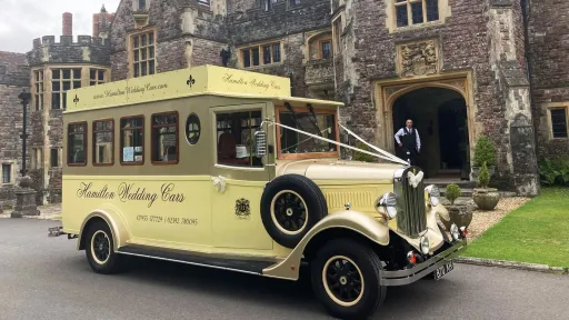Cream and gold Asquith Mascot vintage wedding bus parked outside Rhinefield House in the New Forest