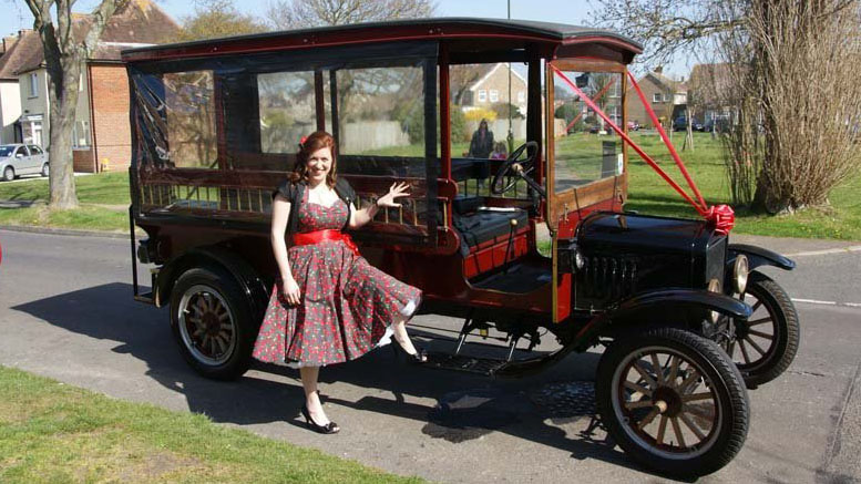 1914 Ford Model T Charabanc wedding bus with passenger wearing 1920s outfit standing beside the vehicle