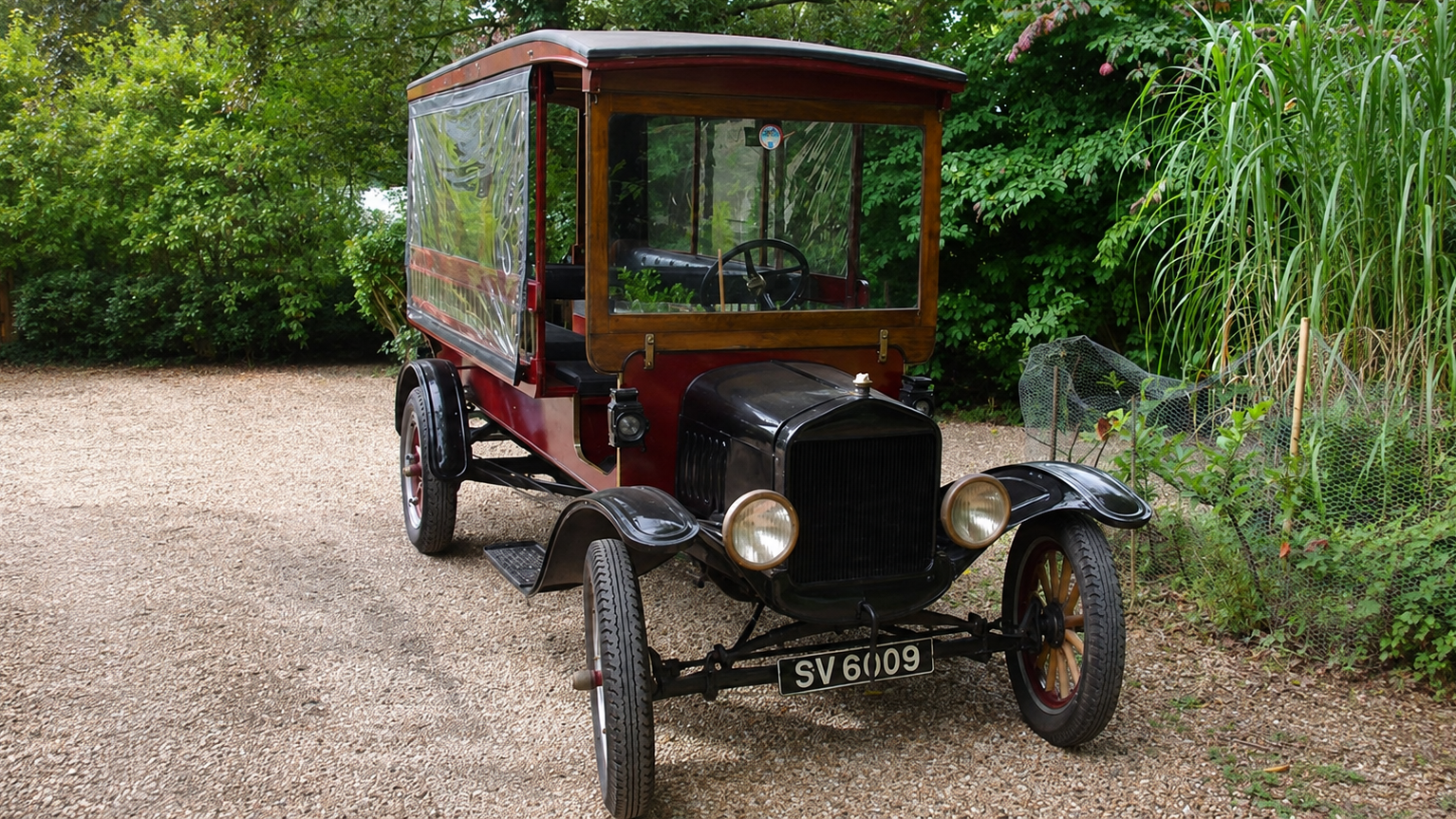 Vintage 1914 Ford Model T Charabanc wedding bus parked beside greenery