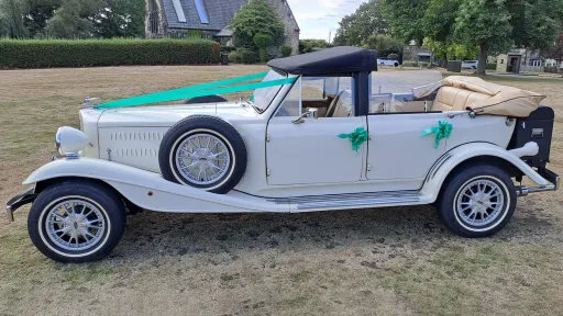Left side view of Old English White four door Beauford Convertible wedding car with roof open and green ribbons