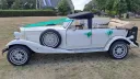 Left side view of Old English White four door Beauford Convertible wedding car with roof open and green ribbons