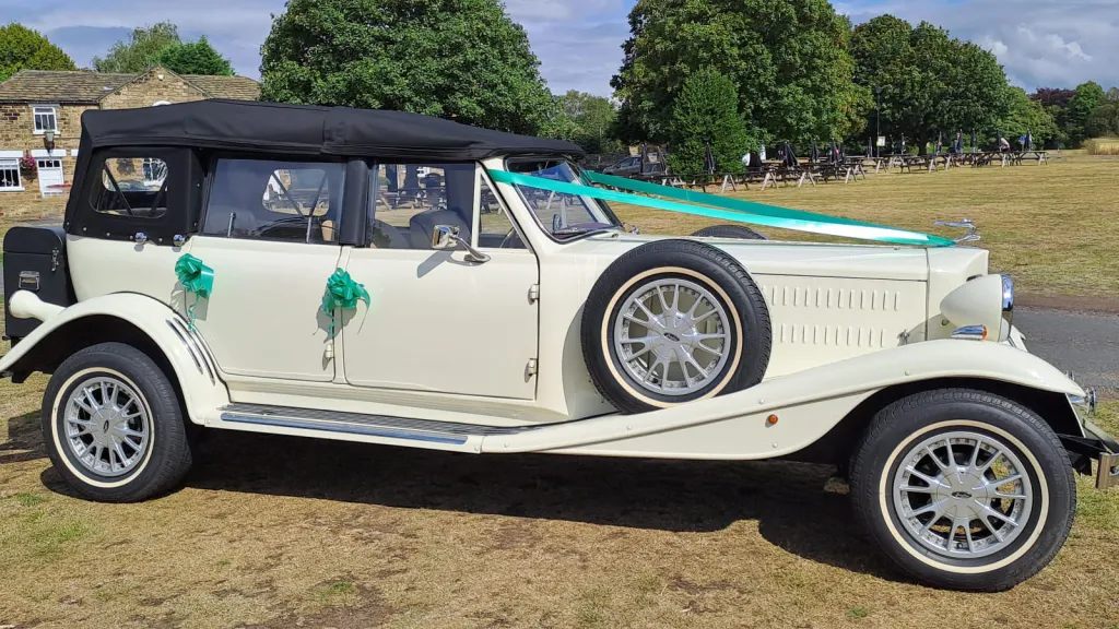 Right side view of Old English White four door Beauford Convertible wedding car with black soft top roof and green ribbons and bows on door handles