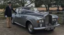 Classic Rolls-Royce Silver Cloud dressed with whitw ribbons and bows and fully uniformed chauffeur standing beside the vehicle