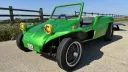 Green 1971 VW beach buggy with the roof removed, showing its open cabin and yellow spotlights