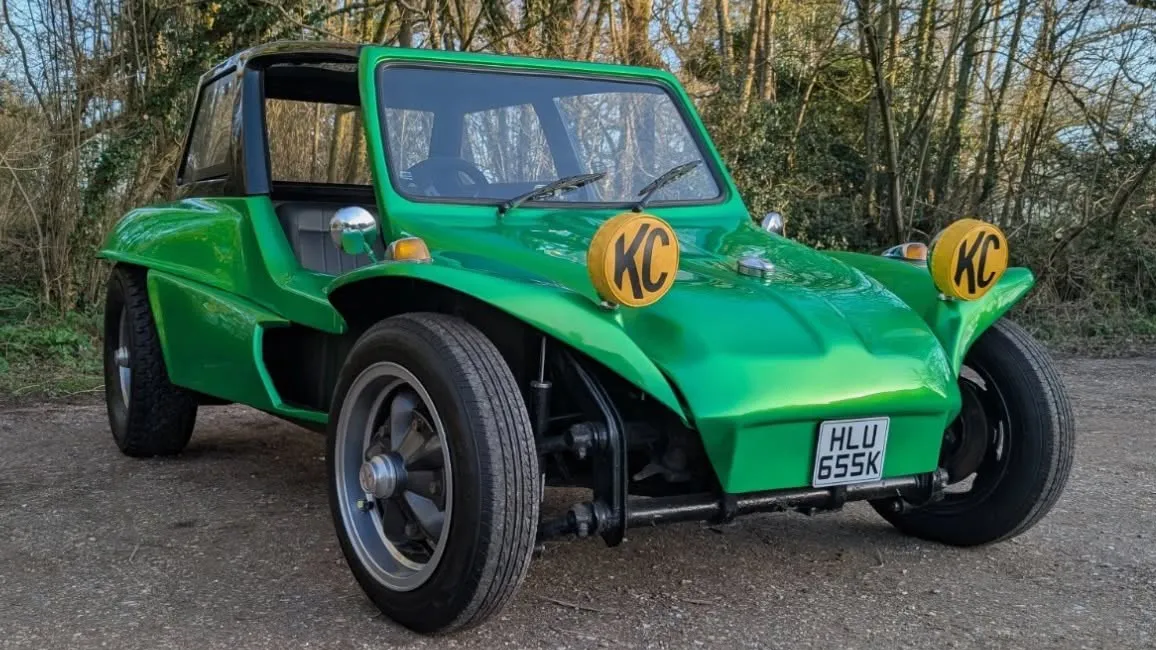 Front three-quarter view of a green classic VW beach buggy with its black roof fitted