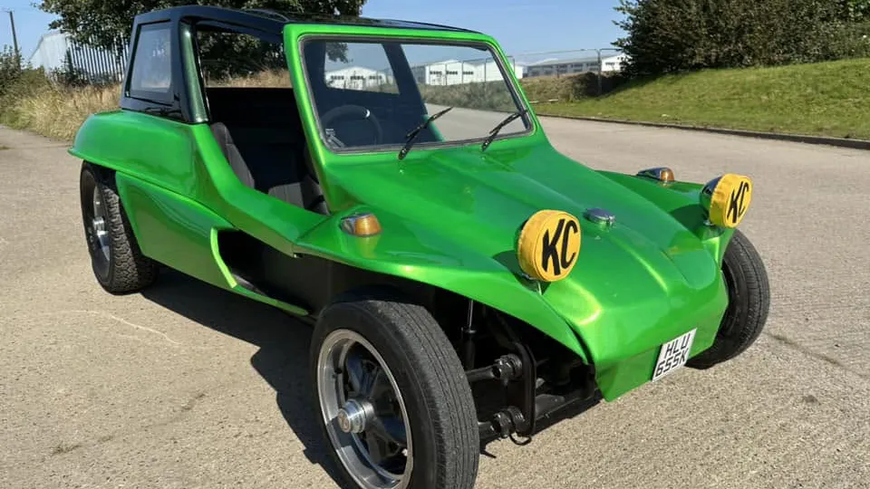 Front side view of a green classic VW beach buggy showing its open doorway and black seats
