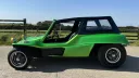 Side profile of a green 1971 Volkswagen beach buggy with a black roof fitted
