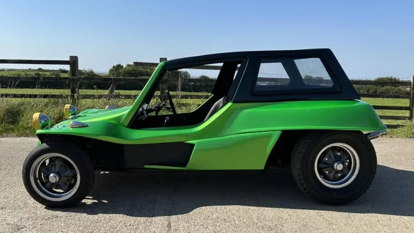 Side profile of a green 1971 Volkswagen beach buggy with a black roof fitted