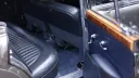 Rear passenger compartment of a classic Jaguar Mk2 with dark blue leather seating and wood door trim