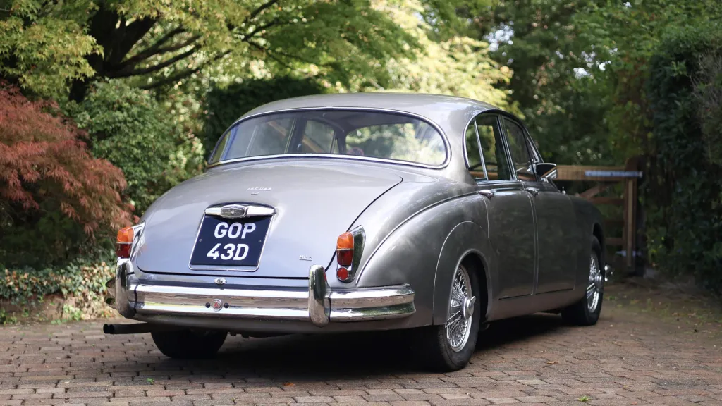 Silver classic Jaguar Mk2 viewed from the rear right on a gravel driveway