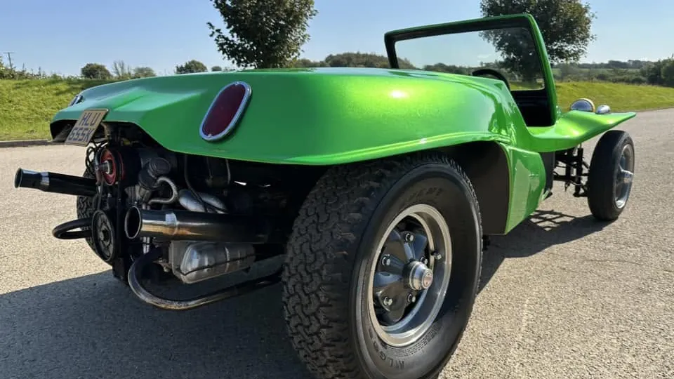 Rear view of a green 1971 VW beach buggy with the roof removed, showing its exposed engine and wide rear tyres