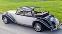 Elevated rear view of an ivory and black Royale Windsor Landaulette with its rear roof folded down.