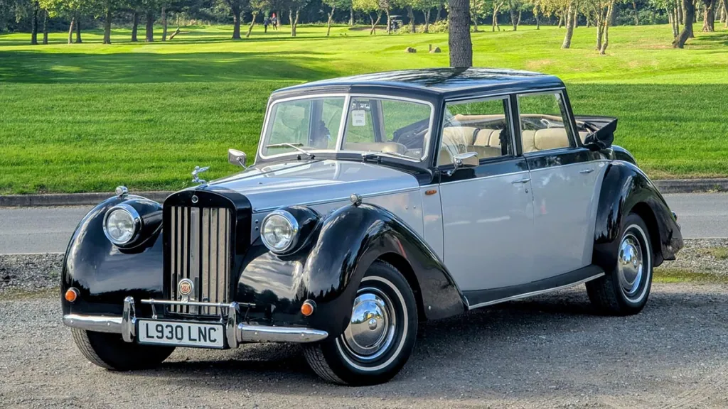 Front three-quarter view of an ivory and black Royale Windsor Landaulette with the rear roof open.