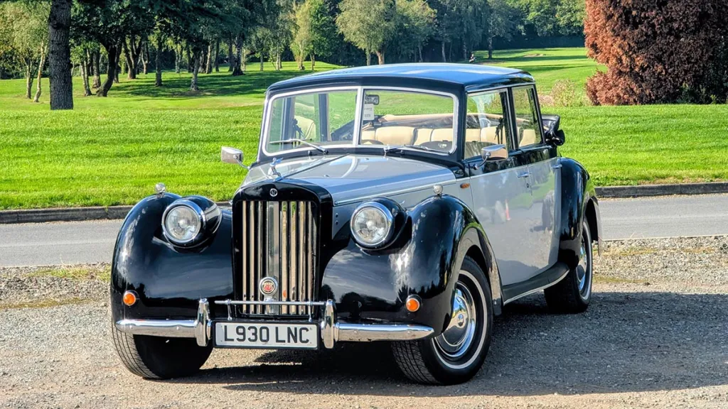 Front view of an ivory and black Royale Windsor wedding car with chrome grille and round headlamps.
