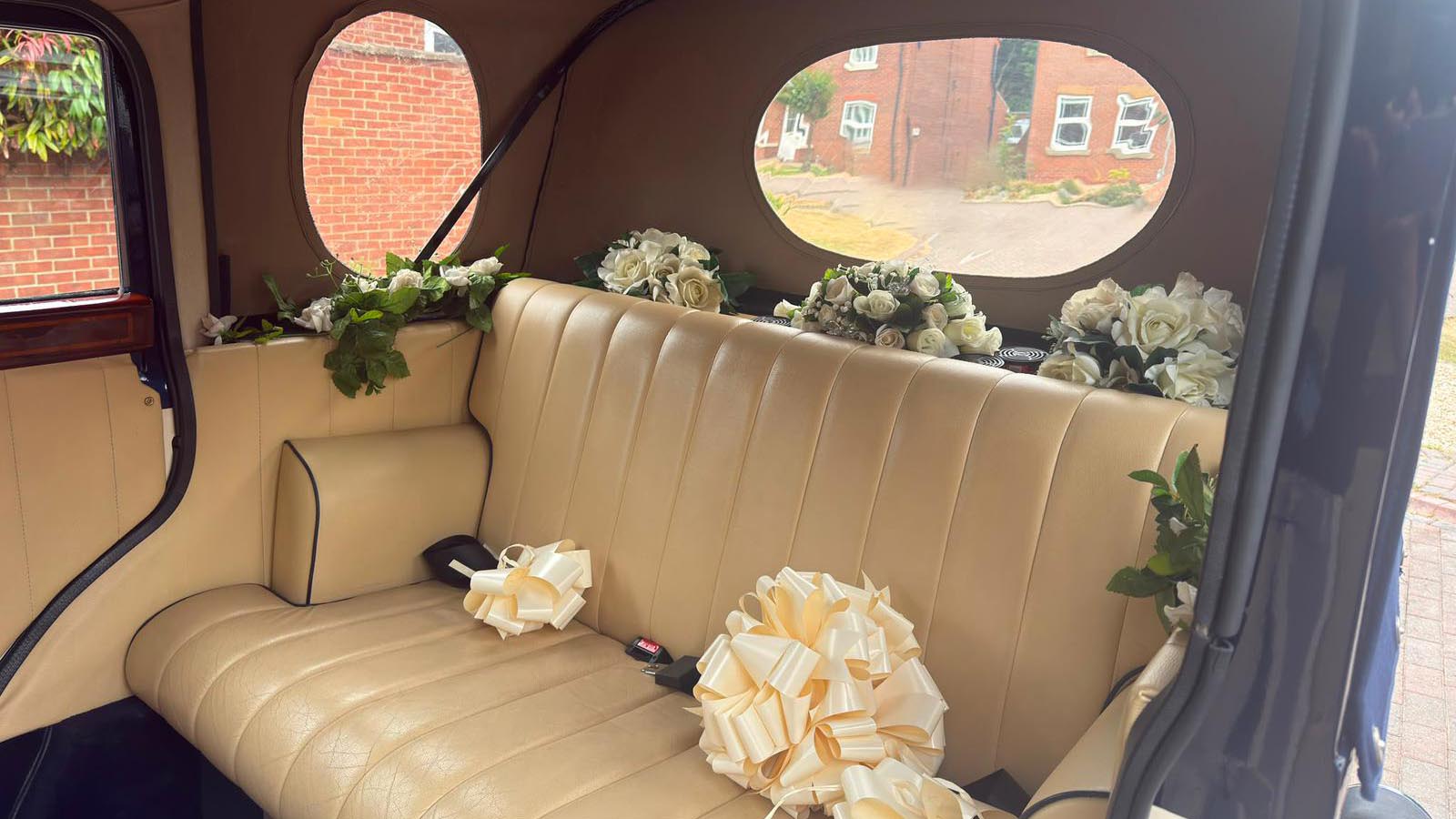 Rear cream leather bench seat with wedding flowers inside the Bramwith Landaulette.
