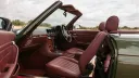 Burgundy leather seats and wooden dashboard inside a 1989 Mercedes-Benz 420 SL with the roof open
