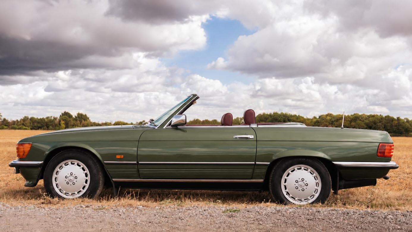 Left side of a green 1989 Mercedes-Benz 420 SL with the roof removed, showing its burgundy interior