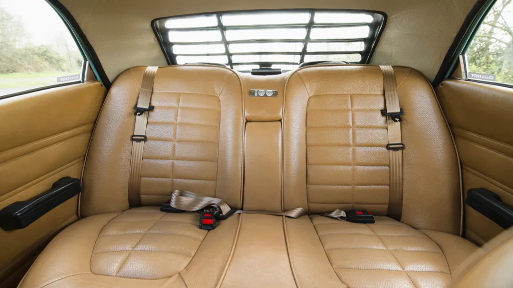 Cream rear bench seat with seat belts inside a Ford Cortina Mk4