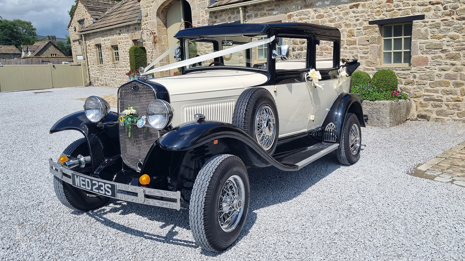 Cream and black Badsworth Landaulette with white wedding ribbons at The Tithe Barn, Bolton Abbey