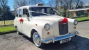 Ivory classic wedding taxi decorated with red ribbons and bows