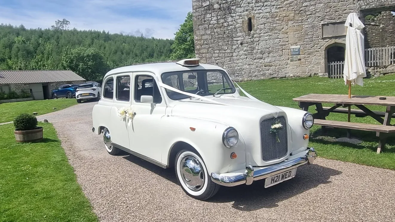 Ivory classic wedding taxi parked beside a stone wedding venue in Yorkshire