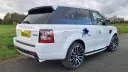 Rear three-quarter view of a white Range Rover Sport Autobiography with blue wedding bows