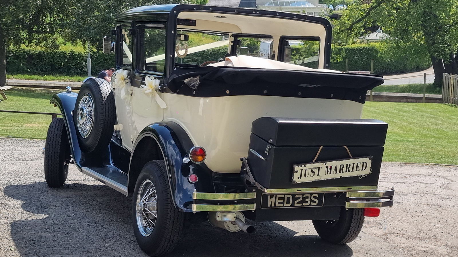 Rear three-quarter view of a Badsworth Landaulette with its rear roof open and Just Married sign