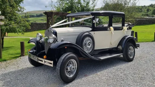 Cream and black Badsworth Landaulette wedding car parked beside a lawn in Yorkshire