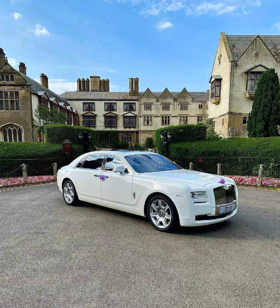 white Rolls-Royce Ghost decorated with purple bows on door handles parked in front of wedding venue in Birmingham