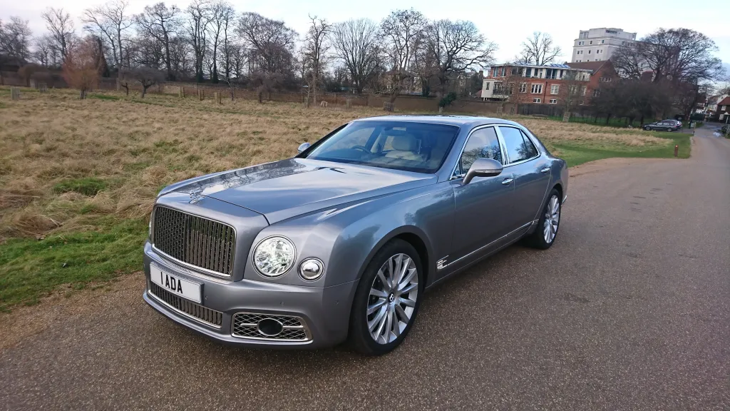 Silver Modern Bentley Mulsanne parked in a park with Autumn colours in the background