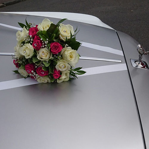 Red and White posy of flower decorated placed on the front bonnet of a silver modern Rolls-Royce