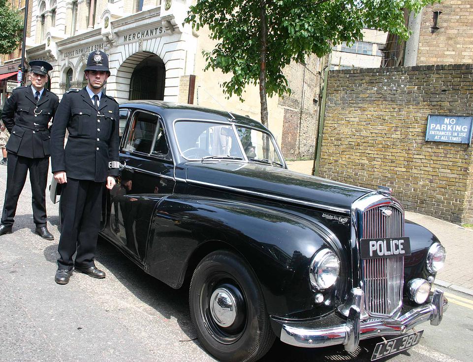 Classic Wolseley Police car in back with two chauffeurs wearing period police uniforms