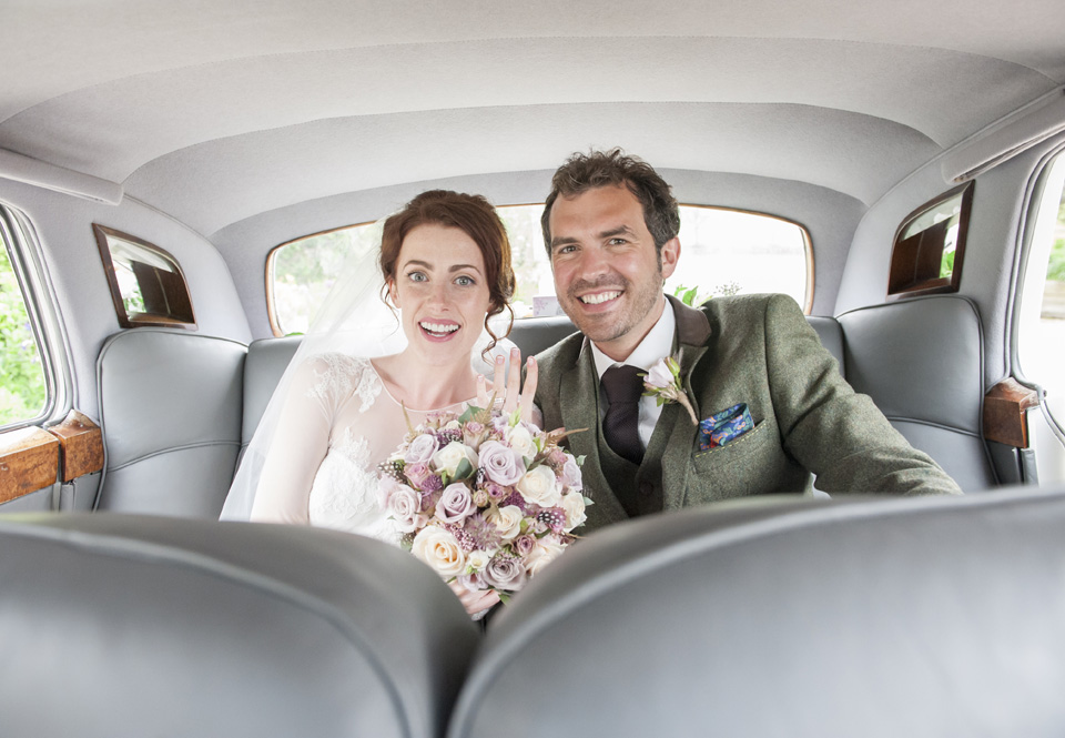 Bride and Groom seated in the back of the Classic Rolls-Royce smiling