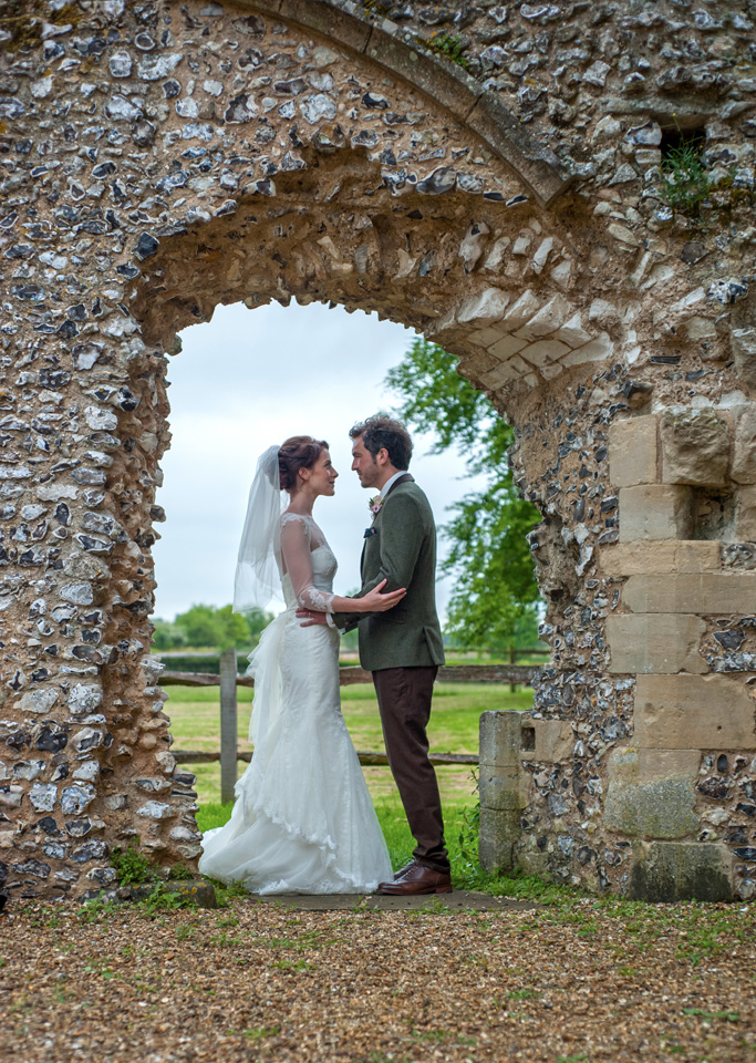 Bride and Groom holding each others under a stone arch at their wedding venue