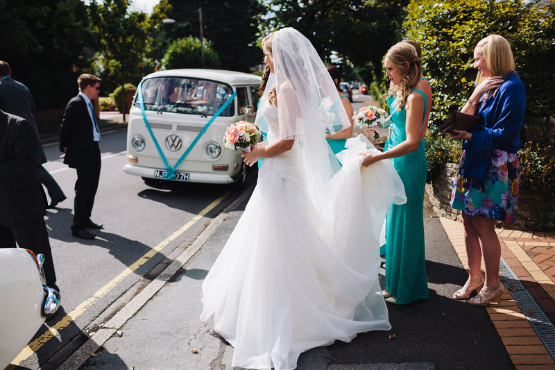 Bride waiting for VW Campervans with Turquoise ribbons matchign the bridesmaids dress