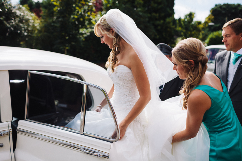 Bride entering the Classic Rolls-Royce with help from one of her bridesmaid